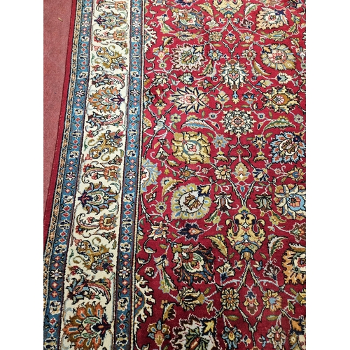 958 - A Red ground Persian Tabriz Carpet with a hand woven and a unique all over floral design nd surround... 