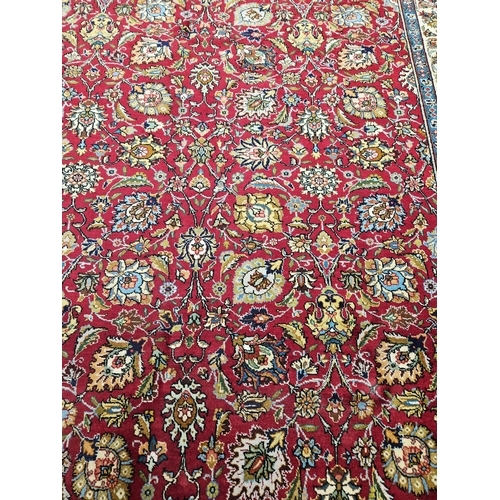 958 - A Red ground Persian Tabriz Carpet with a hand woven and a unique all over floral design nd surround... 