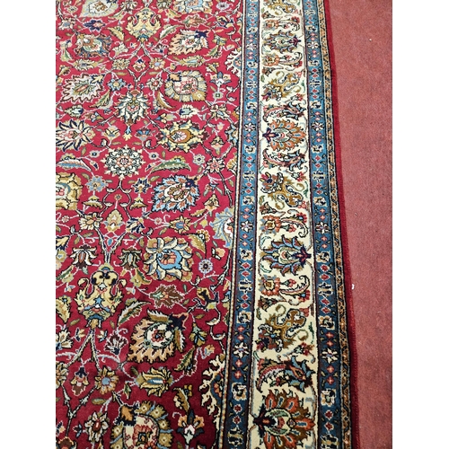 958 - A Red ground Persian Tabriz Carpet with a hand woven and a unique all over floral design nd surround... 