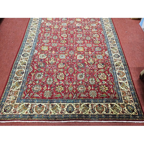 958 - A Red ground Persian Tabriz Carpet with a hand woven and a unique all over floral design nd surround... 