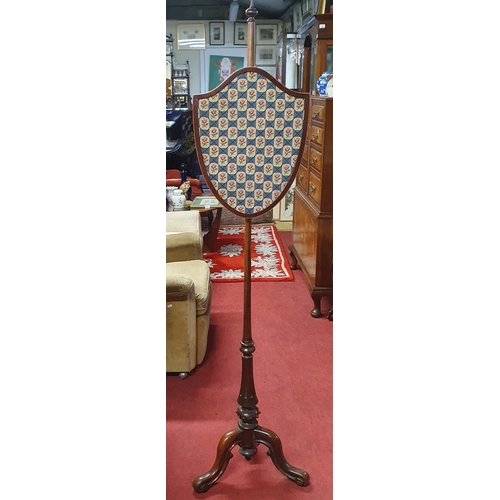 566 - A 19th Century Mahogany Pole Screen with shield shape rise and fall panel and turned fluted support ... 