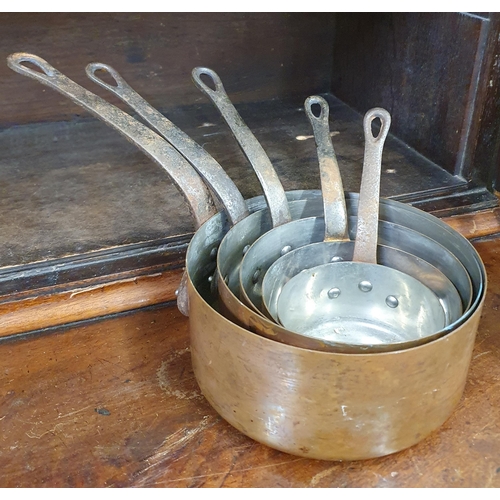 1112 - A graduated set of 19th Century Copper Saucepans with cast iron handles.