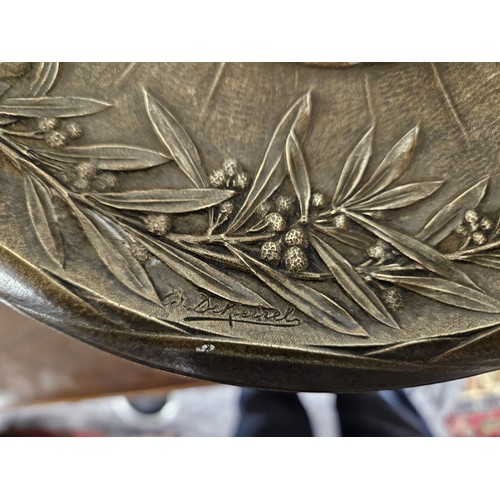 73 - Bronze footed cup with brown patina centered with a medallion decorated with a flower basket and bea... 