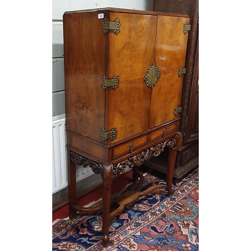 69 - A 20th Century Walnut and Veneered Drinks Cabinet, with mirrored glass insert, highly carved outline... 