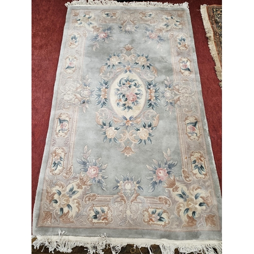 551 - A green ground Oriental Rug with central floral medallion design. 255 x 152 cm approx.