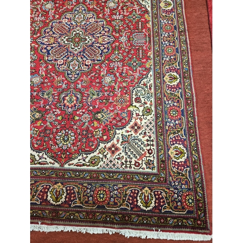 571 - A Red ground hand woven Persian Tabriz Carpet with a floral medallion design.
204 x 310 cm approx.