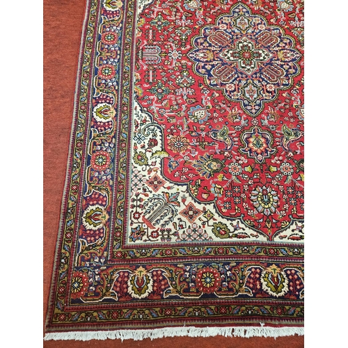 571 - A Red ground hand woven Persian Tabriz Carpet with a floral medallion design.
204 x 310 cm approx.