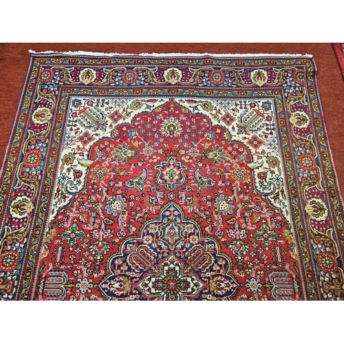 571 - A Red ground hand woven Persian Tabriz Carpet with a floral medallion design.
204 x 310 cm approx.