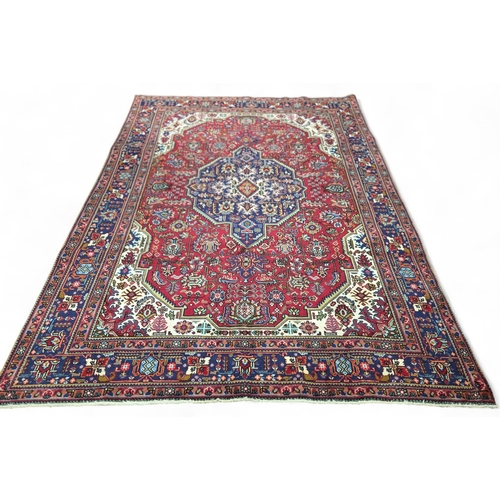 13 - A Stunning Red ground handwoven Persian Tabriz Carpet with a multi coloured design and a central med... 