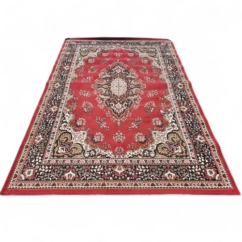 427 - A large European red ground Rug with central floral motif floral spandrels and multiple floral borde... 