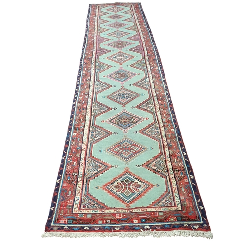 219 - A Persian red and green ground Runner with repeating central medallion design and multi borders. 407... 