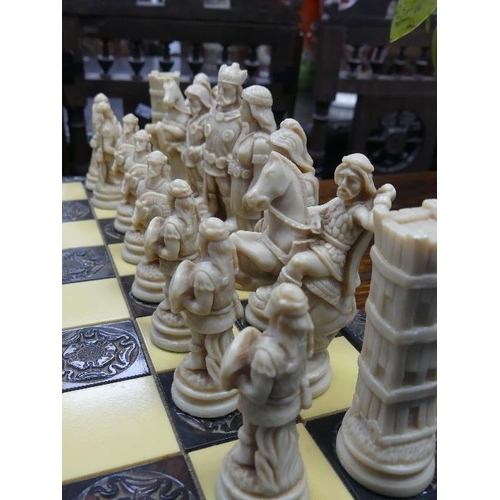 172 - A resin Chess Set, the board with carved wooden frame, 17¾in (45cm) wide.