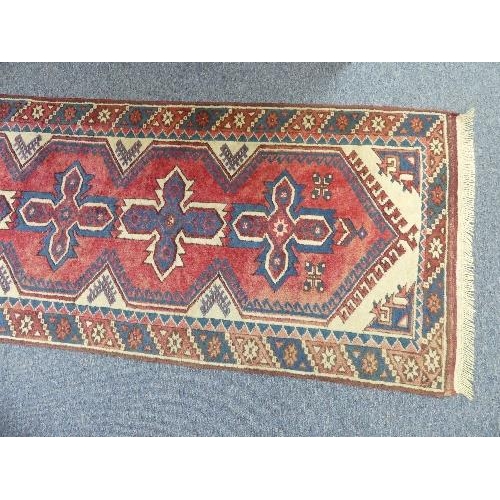 206 - Tribal Rugs; a Turkish Runner, the light red ground with seven central cross-shaped medallions set w... 