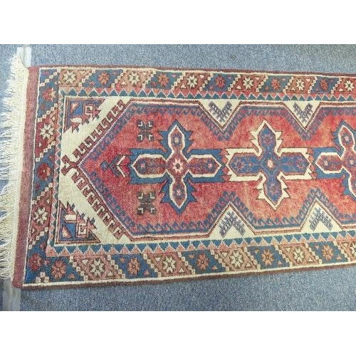 206 - Tribal Rugs; a Turkish Runner, the light red ground with seven central cross-shaped medallions set w... 