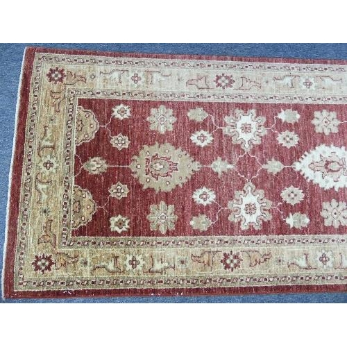 211 - Tribal Rugs; a Zeigler-style runner, the claret-coloured groun woven with gold-coloured oriental pat... 