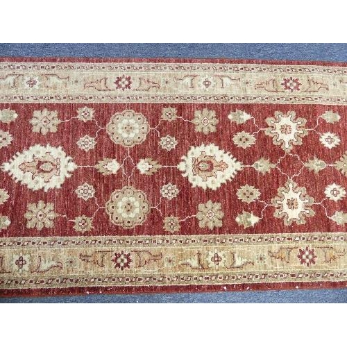 211 - Tribal Rugs; a Zeigler-style runner, the claret-coloured groun woven with gold-coloured oriental pat... 