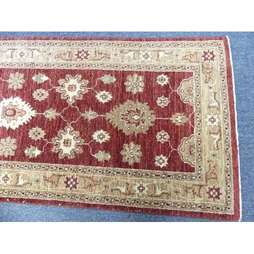 211 - Tribal Rugs; a Zeigler-style runner, the claret-coloured groun woven with gold-coloured oriental pat... 