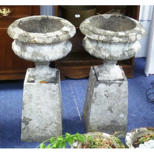 251 - A pair of reconstituted stone garden Urns, with plinths, 34in (86.5cm) high (2)