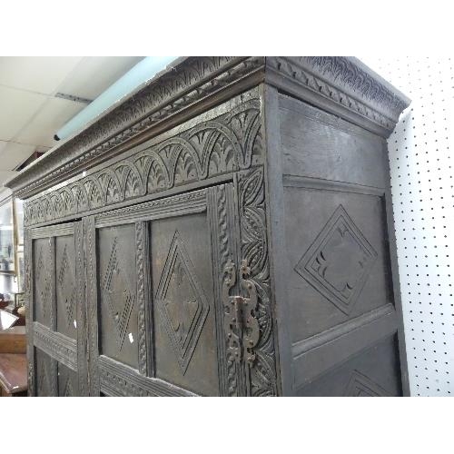 480 - An antique carved oak two-drawer Cupboard, the cornice above panelled sides and doors, the whole car... 