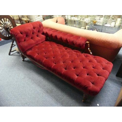 104 - A Late Victorian mahogany-framed Chaise Longue, button-back with red upholstery, raised on turned le... 