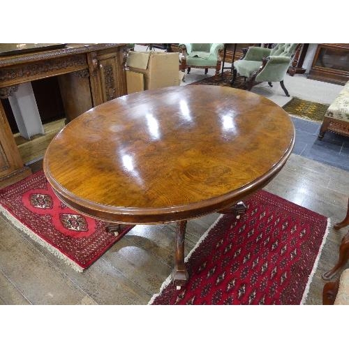 84 - A Victorian walnut oval Breakfast Table, quarter veneered top above a deep frieze, turned quatre-col... 