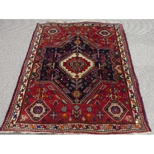 90 - Tribal rugs; a Persian Qashqai red and blue ground rug, the whole woven with stylised tree of life a... 