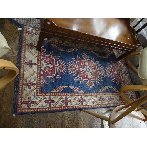 91 - Tribal Rugs; two pale blue ground small rugs, each with stylised geometric patterns in cream, light ... 