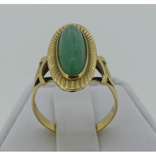 117 - A 14ct yellow gold oval Dress Ring, with a narrow cabchon jade centre within a gold sunburst border,... 