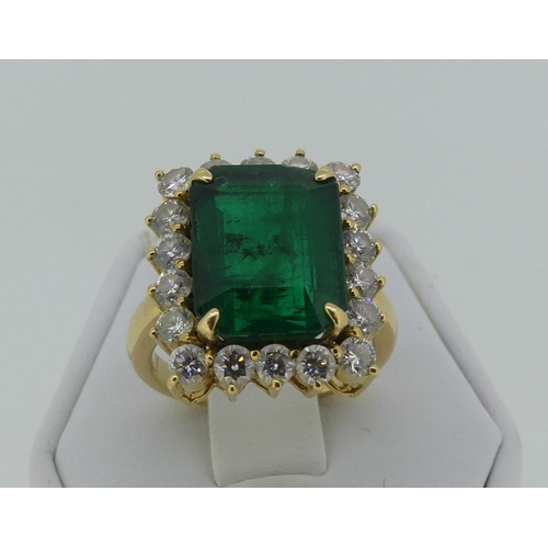 120 - A large emerald and diamond Dress Ring, the central emerald cut stone circa 7cts (39mm x 6.6mm)surro... 