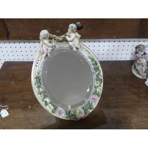 107 - A late 19th century continental porcelain oval easel Mirror, the frame applied with roses and surmou... 