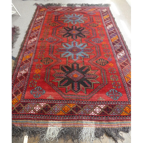 396 - Tribal rugs; an old Caucasian Kazak red ground rug, coarsely woven and hand knotted with four centra... 