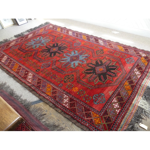 396 - Tribal rugs; an old Caucasian Kazak red ground rug, coarsely woven and hand knotted with four centra... 