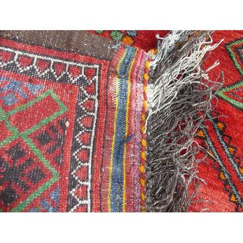 396 - Tribal rugs; an old Caucasian Kazak red ground rug, coarsely woven and hand knotted with four centra... 