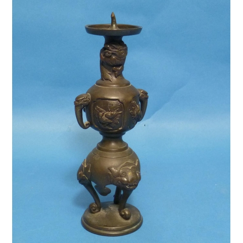 66 - An antique Oriental bronze Candlestick, embossed in relief with three-toed dragons, dogs of Foo, bir... 