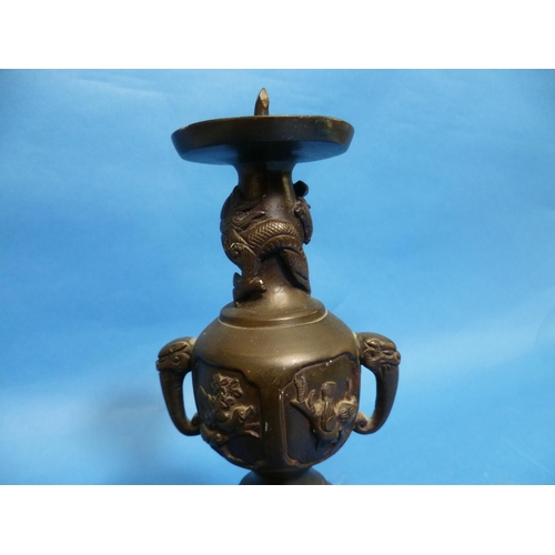 66 - An antique Oriental bronze Candlestick, embossed in relief with three-toed dragons, dogs of Foo, bir... 