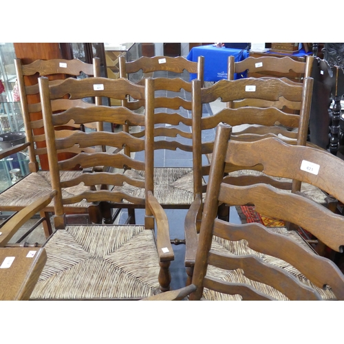 415A - A set of six oak ladder-back dining elbow chairs, with shaped splats, rush seats and turned legs joi... 