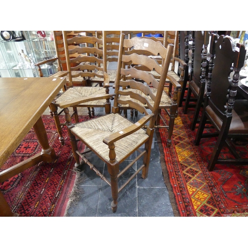 415A - A set of six oak ladder-back dining elbow chairs, with shaped splats, rush seats and turned legs joi... 