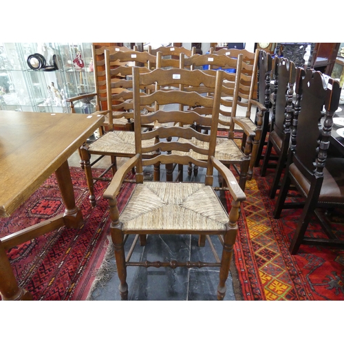 415A - A set of six oak ladder-back dining elbow chairs, with shaped splats, rush seats and turned legs joi... 