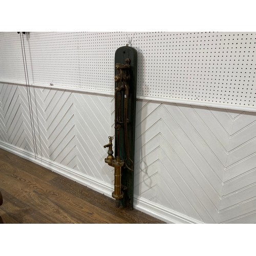 343 - A 19thC standing brass and iron hand-operated Water Pump, on green painted back board, H 155cm x W31... 