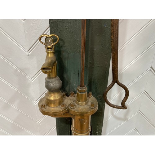 343 - A 19thC standing brass and iron hand-operated Water Pump, on green painted back board, H 155cm x W31... 