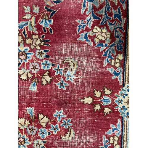 286 - Tribal Rugs; an old hand-knotted wool Persian carpet, red ground with blue border and central medall... 