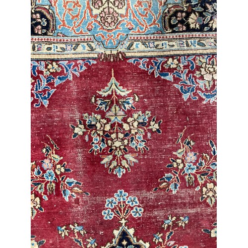 286 - Tribal Rugs; an old hand-knotted wool Persian carpet, red ground with blue border and central medall... 