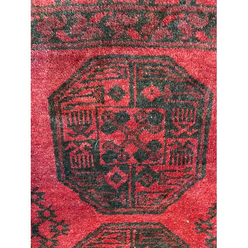 280 - Tribal Rugs: a red ground Afghan hand knotted rug, the whole woven with tekke and guls within a wide... 