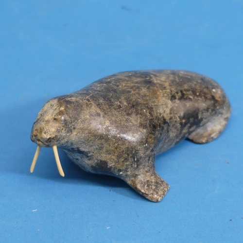 352 - A 20thC Inuit stone carving of a walrus, with bone tusks, L 13cm, together with an Inuit stone carvi... 