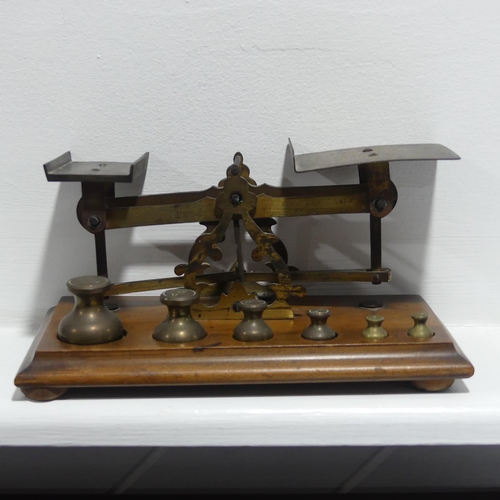 420 - An antique set of brass Postal Scales, on wooden base, with complete set of six weights, the base 21... 