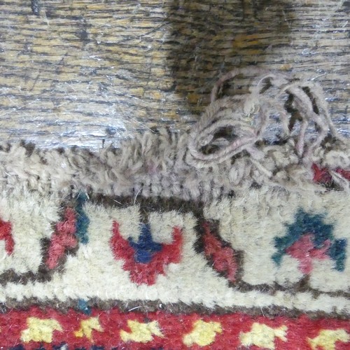 628 - Tribal Rugs; a Persian hand-knotted rug, wool pile on cotton base, overall poor condition with holes... 