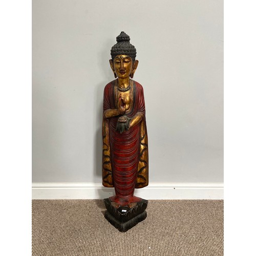 531 - A Thai carved and gilt wood standing figure of a priest, holding a flower in one hand, on triangular... 