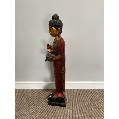 531 - A Thai carved and gilt wood standing figure of a priest, holding a flower in one hand, on triangular... 