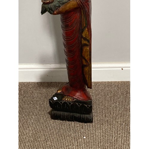 531 - A Thai carved and gilt wood standing figure of a priest, holding a flower in one hand, on triangular... 