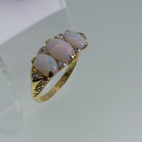 98 - An early 20thC graduated three stone opal Ring, each with two diamond points set vertically  between... 